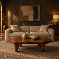 Low bean shaped coffee table with a rich grained top and four tapered legs in a dark living room at golden hour