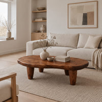 Low bean shaped coffee table with a rich grained top and four tapered legs in a Scandinavian living room with white walls