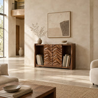 Low bookshelf with two carved wave doors and open bays at both ends in a bright open plan living room