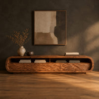 Low capsule shaped tv stand with wave carved fronts and open bays in a dark studio against a charcoal plaster wall
