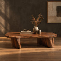 Low coffee table with a thick slab top and two boat shaped legs in a dark studio against a charcoal plaster wall