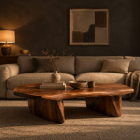 Low coffee table with a thick slab top and two boat shaped legs in a dark living room at golden hour