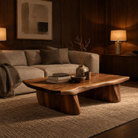 Low coffee table with a thick slab top and two boat shaped legs in an evening living room with walnut wall paneling
