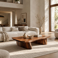 Low coffee table with a thick slab top and two boat shaped legs in a bright open plan living room