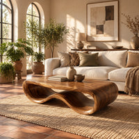 Low oval wooden coffee table with a folded ribbon body in a bright living room with arched windows and plants