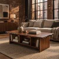 Low coffee table with a wavy natural edge top and three open cubbies in an industrial loft living room with exposed brick