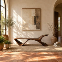 Low wooden bench with a swept up end and an open triangle leg in a bright entryway with arched windows and plants