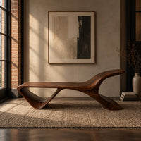 Low wooden bench with a swept up end and an open triangle leg in an industrial loft entryway with exposed brick
