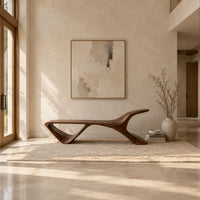 Low wooden bench with a swept up end and an open triangle leg in a bright open plan entryway
