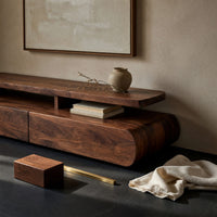 Corner detail of low drawer plinth TV stand with a floating shelf beside wood, brass and linen samples