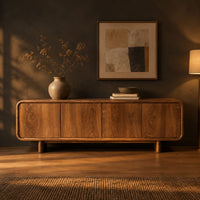 Low wood sideboard with four flat front panels and short legs in a dark dining room at golden hour