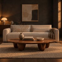 Low oval coffee table with a thick top and chunky pod shaped legs in a dark living room at golden hour