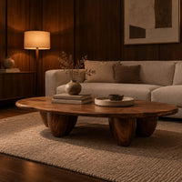 Low oval coffee table with a thick top and chunky pod shaped legs in an evening living room with walnut wall paneling