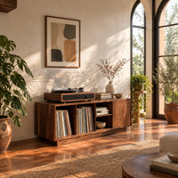Low wood record console with three open cubbies and a panel end in a bright living room with arched windows and plants