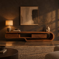Low tv stand shaped like a looping wood ribbon with two boxed front sections in a dark living room at golden hour