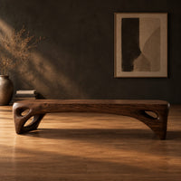 Low slab top bench with open triangular legs in a dark studio against a charcoal plaster wall