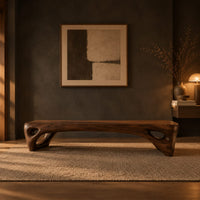 Low slab top bench with open triangular legs in a dark entryway at golden hour