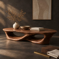 Corner detail of low coffee table with an oval top and twin open loops beside wood, brass and linen samples