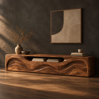 Low wood tv stand with a rippling carved front and an open top slot, three-quarter view showing the grain