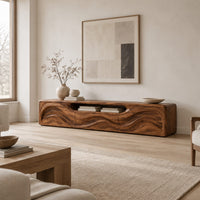 Low wood tv stand with a rippling carved front and an open top slot in a Scandinavian living room with white walls