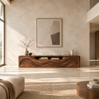Low wood tv stand with a rippling carved front and an open top slot in a bright open plan living room