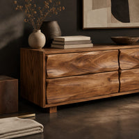 Corner detail of low bench with four wavy grain front panels on short block feet beside wood, brass and linen samples
