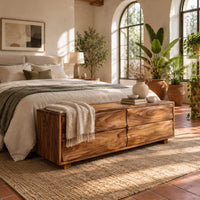 Low bench with four wavy grain front panels on short block feet in a bright bedroom with arched windows and plants