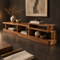 Corner detail of low stepped open shelf console table with a raised section at one end beside wood, brass and linen samples