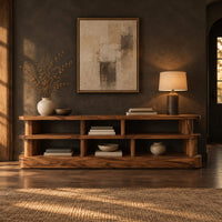 Low stepped open shelf console table with a raised section at one end in a dark entryway at golden hour