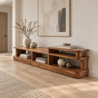 Low stepped open shelf console table with a raised section at one end in a Scandinavian entryway with white walls