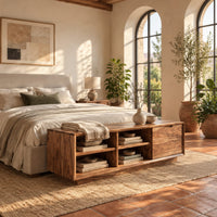 Low storage bench with four open cubbies and a closed wood panel in a bright bedroom with arched windows and plants