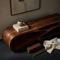 Corner detail of low TV console with a carved crossing hollow beside wood, brass and linen samples