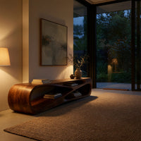 Low TV console with a carved crossing hollow in an evening room lit by two lamps