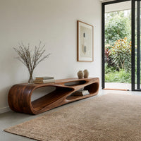 Low TV console with a carved crossing hollow in an open plan space in daylight