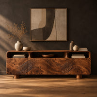 Low wood tv stand with a carved wave front and open top compartments in a dark studio against a charcoal plaster wall