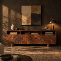 Low wood tv stand with a carved wave front and open top compartments in a dark living room at golden hour