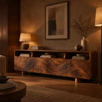 Low wood tv stand with a carved wave front and open top compartments in an evening living room with walnut wall paneling