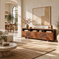 Low wood tv stand with a carved wave front and open top compartments in a bright open plan living room