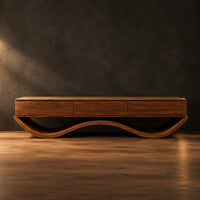 Low tv stand with three front panels on a wave shaped base in a dark studio against a charcoal plaster wall