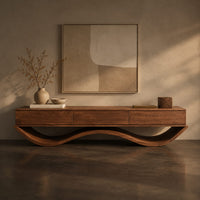 Corner detail of low tv stand with three front panels on a wave shaped base beside wood, brass and linen samples