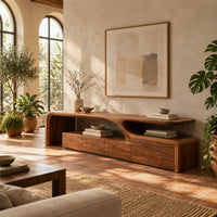 Low tv stand with a sweeping wave top and a four panel front in a bright living room with arched windows and plants