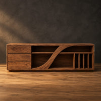 Low tv stand with three drawers and a swooping divider beside vertical slots in a dark studio against a charcoal plaster wall