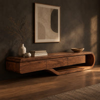 Corner detail of low tv stand with a three panel front and a sweeping curved loop base beside wood, brass and linen samples