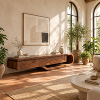 Low tv stand with a three panel front and a sweeping curved loop base in a bright living room with arched windows and plants