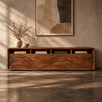 Corner detail of low tv stand with four open cubbies above wave carved front panels beside wood, brass and linen samples