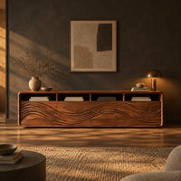 Low tv stand with four open cubbies above wave carved front panels in a dark living room at golden hour