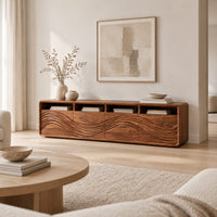 Low tv stand with four open cubbies above wave carved front panels in a Scandinavian living room with white walls