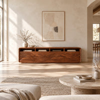 Low tv stand with four open cubbies above wave carved front panels in a bright open plan living room