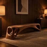 Low solid wood bench with an arched underside and open cutouts at each end in an evening entryway with walnut wall paneling