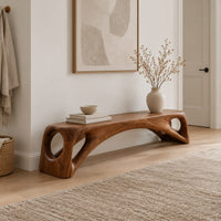 Low solid wood bench with an arched underside and open cutouts at each end in a Scandinavian entryway with white walls